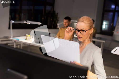 Image of businesswoman with papers working at night office