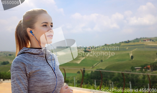 Image of sportswoman in earphones running outdoors