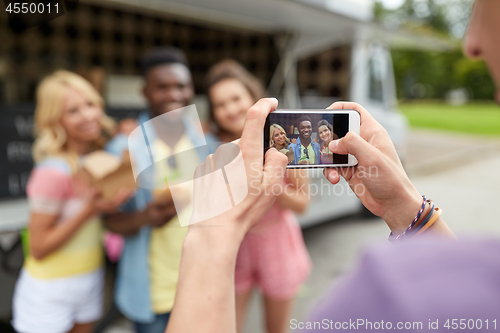 Image of man taking picture of friends eating at food truck