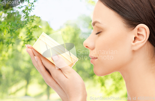 Image of beautiful woman smelling moisturizing cream aroma