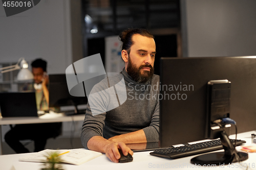 Image of creative man with computer working at night office