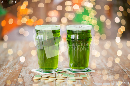 Image of glasses of green beer and gold coins on table