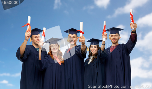 Image of graduates in mortar boards with diplomas