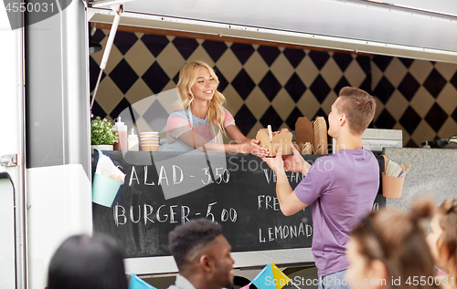 Image of saleswoman at food truck serving male customer