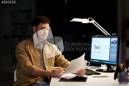 Image of designer with papers working at night office