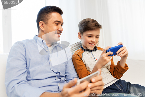 Image of happy father and son with smartphones at home