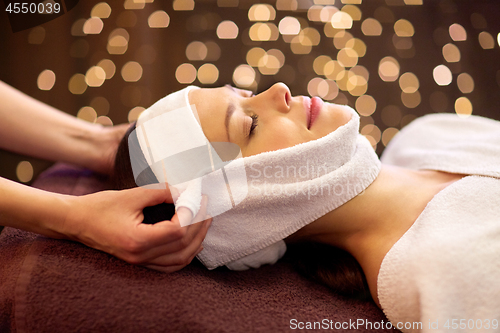 Image of woman having face massage with towel at spa