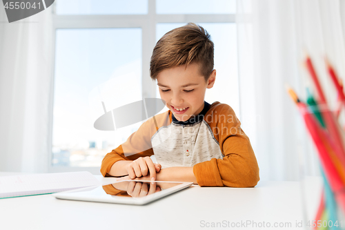 Image of student boy with tablet pc and notebook at home