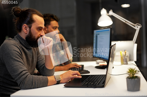 Image of creative team with computer working late at office