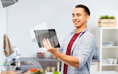 Image of happy young man with tablet computer in kitchen