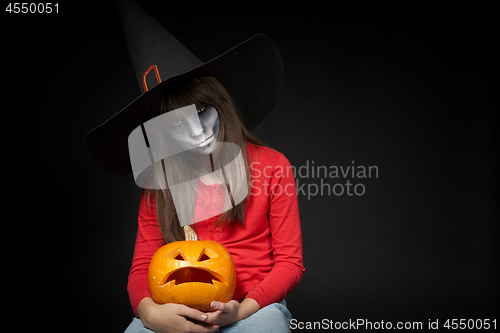 Image of Serious Halloween witch holding Jack O\'Lantern pumpkin looking at camera