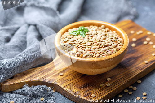 Image of Dry brown lentils in a wooden bowl.