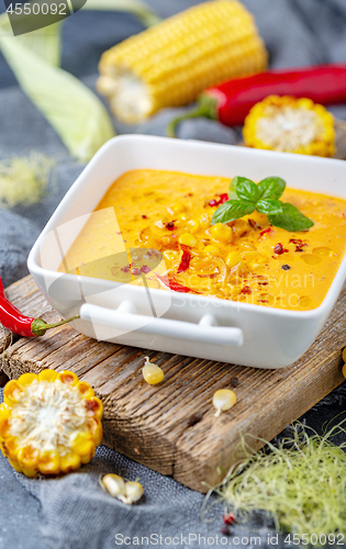 Image of Homemade creamy corn soup in a porcelain saucepan.