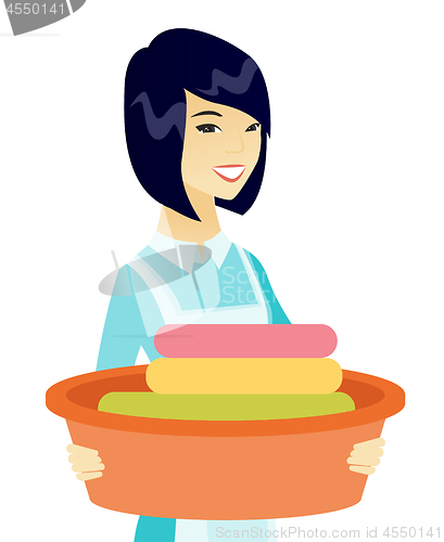 Image of Asian housewife holding basin with dirty linen.