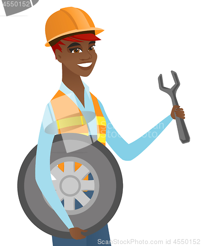 Image of Young african mechanic with tyre and spanner.