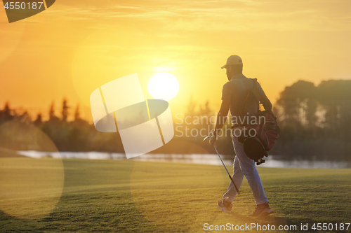 Image of handsome middle eastern golfer carrying bag and walking to next 