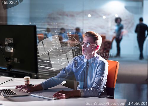 Image of man working on computer in dark office