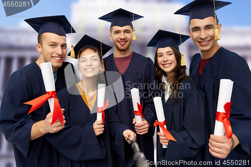 Image of happy graduates with diplomas taking selfie