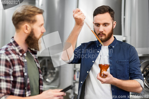 Image of men with pipette testing craft beer at brewery