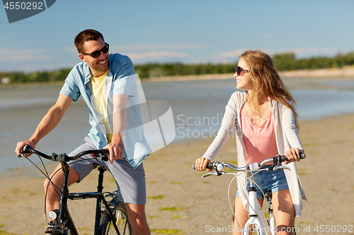 Image of happy young couple riding bicycles at seaside