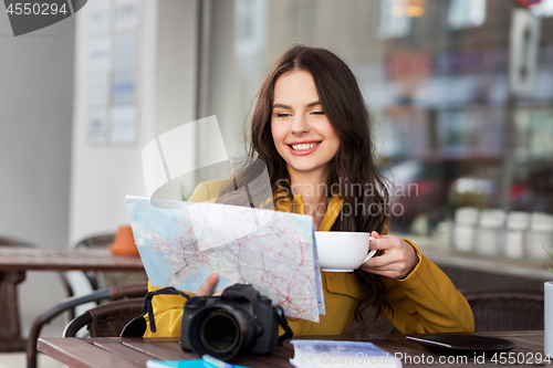 Image of happy woman with map drinking cocoa at city cafe