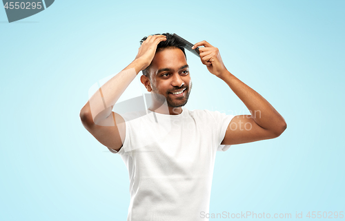 Image of happy indian man brushing hair with comb