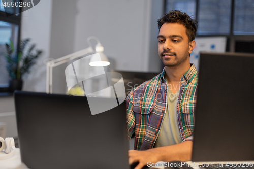 Image of creative man with laptop working at night office