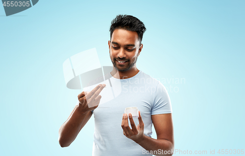 Image of happy indian man applying cream to face