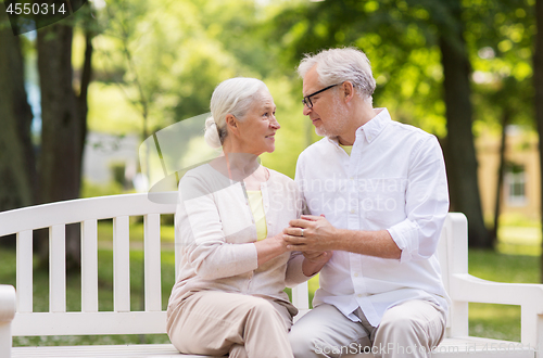 Image of happy senior couple sitting on bench at park