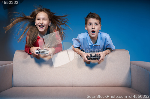 Image of Computer game competition. Gaming concept. Excited girl playing video game with joystick