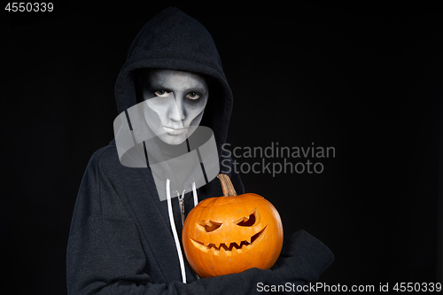 Image of Boy with Halloween makeup holding Jack O\'Lantern pumpkin on black background