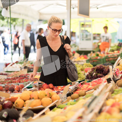 Image of Woman buying fruits and vegetables at local food market. Market stall with variety of organic vegetable