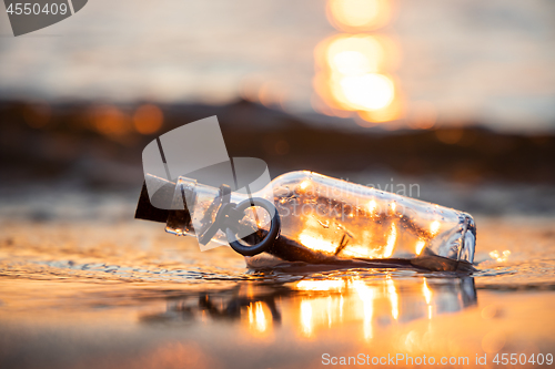 Image of Message in the bottle against the Sun setting down