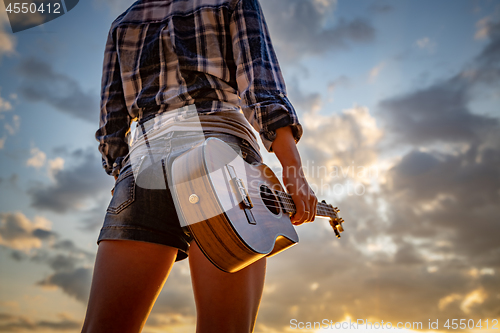 Image of Woman at sunset holding a ukulele