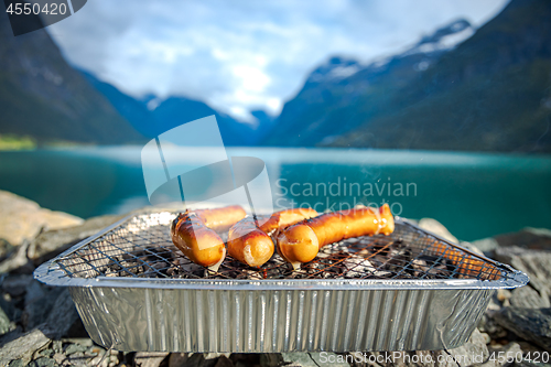 Image of Grilling sausages on disposable barbecue grid.