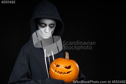 Image of Boy with Halloween makeup holding Jack O\'Lantern pumpkin on black background