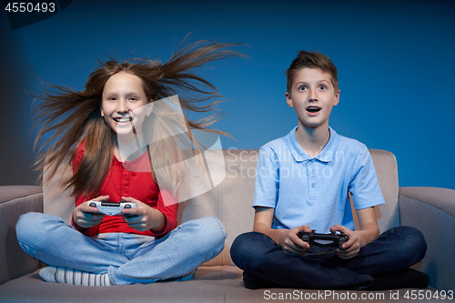 Image of Computer game competition. Gaming concept. Excited girl playing video game with joystick