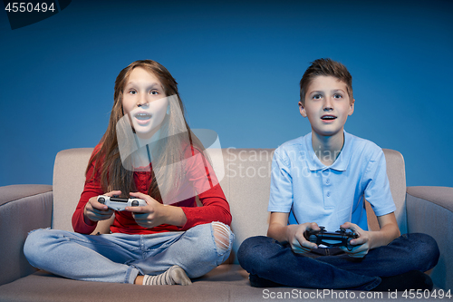 Image of Computer game competition. Gaming concept. Excited girl playing video game with joystick