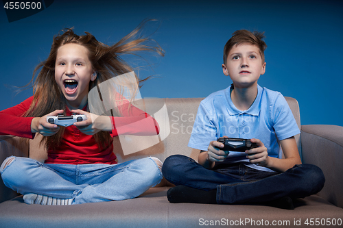 Image of Computer game competition. Gaming concept. Excited girl playing video game with joystick