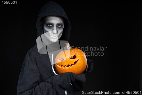 Image of Boy with Halloween makeup holding Jack O\'Lantern pumpkin on black background