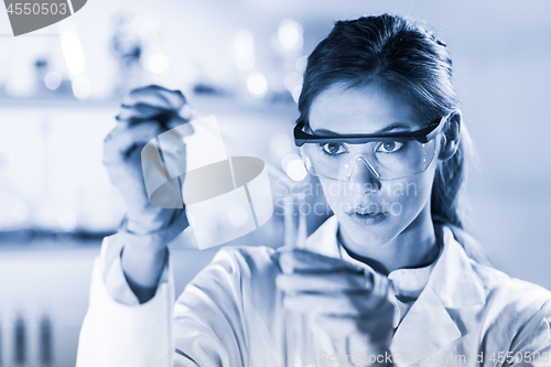 Image of Young scientist pipetting in life science laboratory.