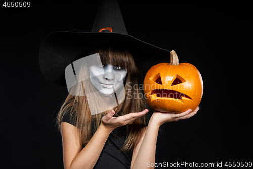 Image of Halloween witch girl showing Jack-O-Lantern pumpkin on palm