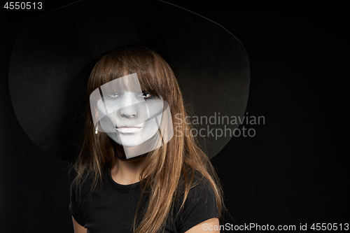 Image of Serious Halloween witch holding Jack-O-Lantern pumpkin looking at camera