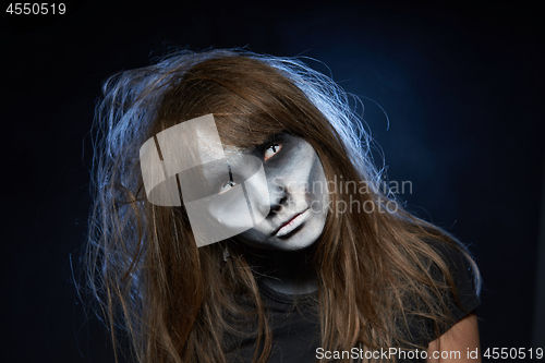 Image of A girl with zombie makeup over dark background with smoke and backlight