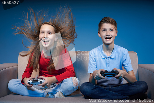 Image of Computer game competition. Gaming concept. Excited girl playing video game with joystick