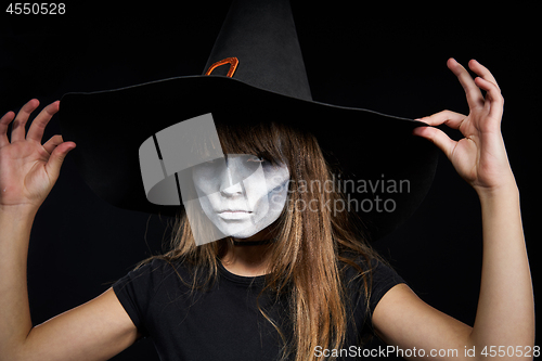 Image of Closeup of Halloween witch girl looking at camera on black background.