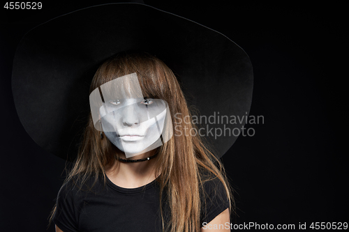 Image of Closeup of Halloween witch girl looking at camera on black background.