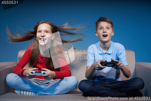 Image of Computer game competition. Gaming concept. Excited girl playing video game with joystick