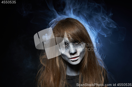 Image of A girl with zombie makeup over dark background with smoke and backlight