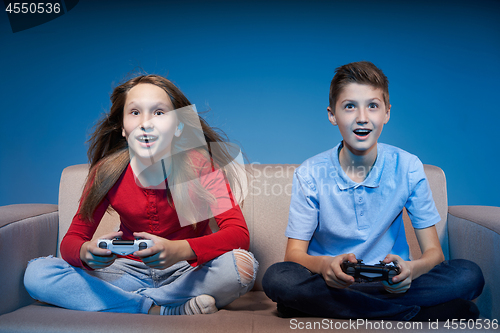 Image of Computer game competition. Gaming concept. Excited girl playing video game with joystick